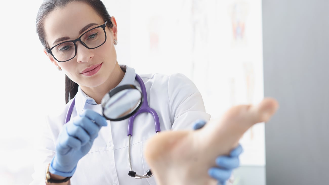 Médecin de famille examinant un pied à la loupe
