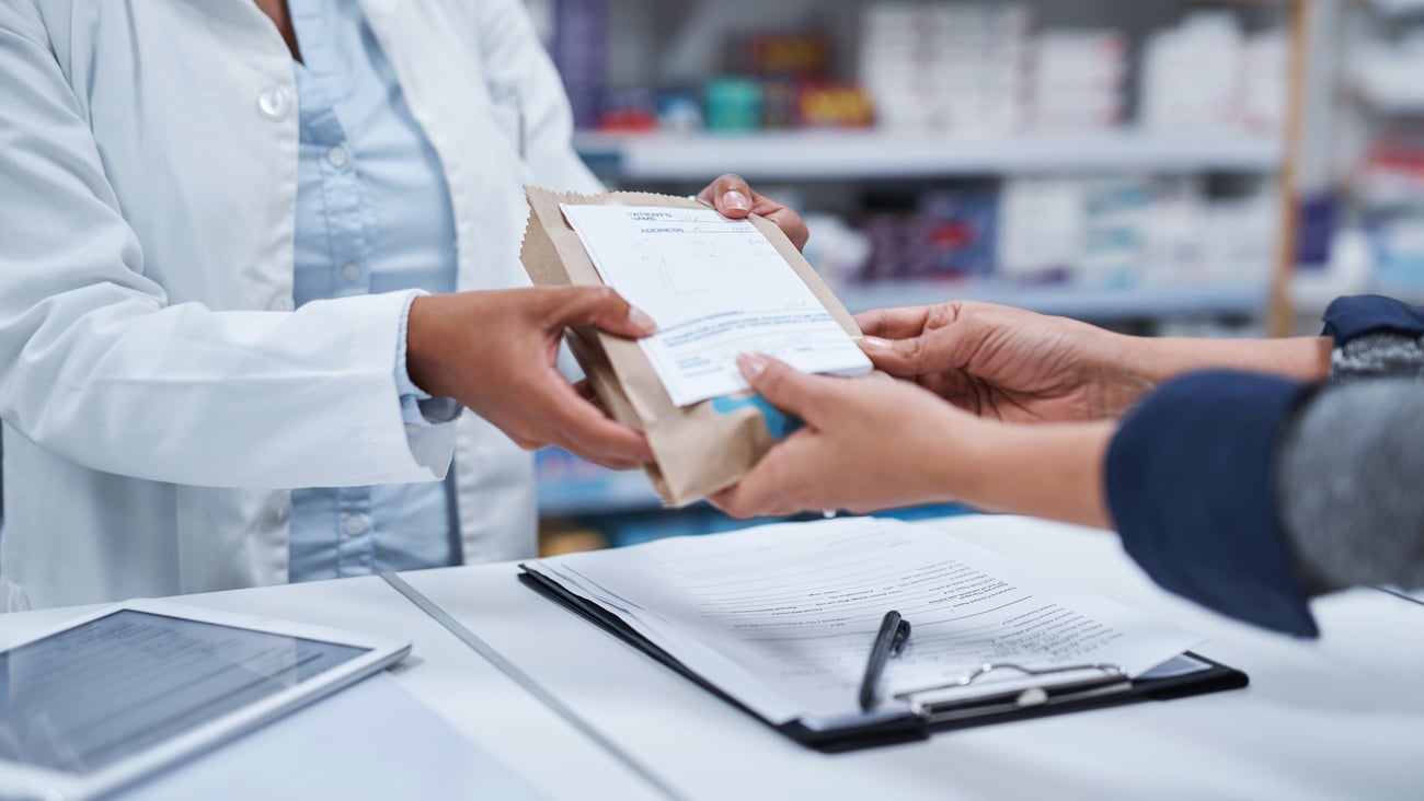 Remise d'un traitement et d'une ordonnance au comptoir d'une pharmacie.