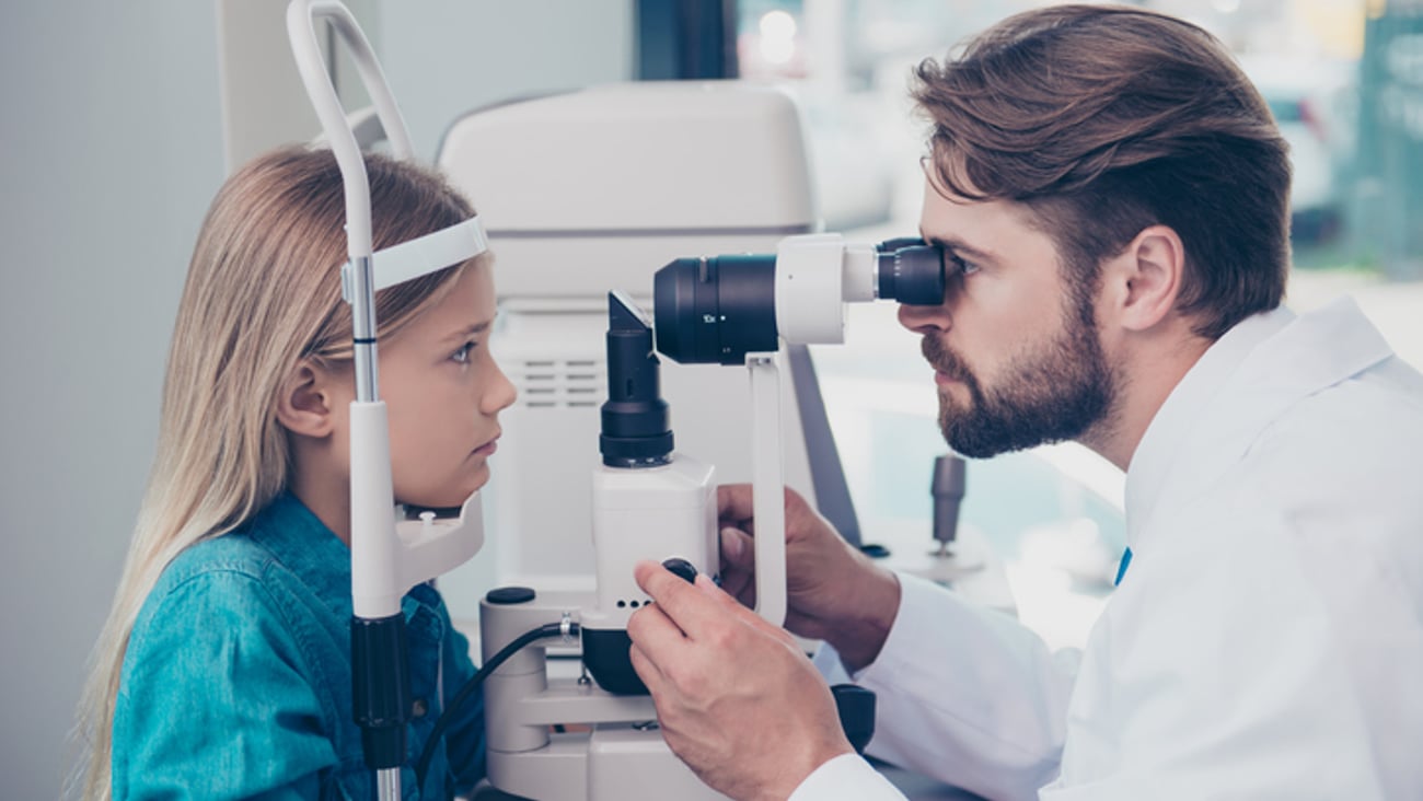 Une enfant se fait examiner les yeux par un optométriste.