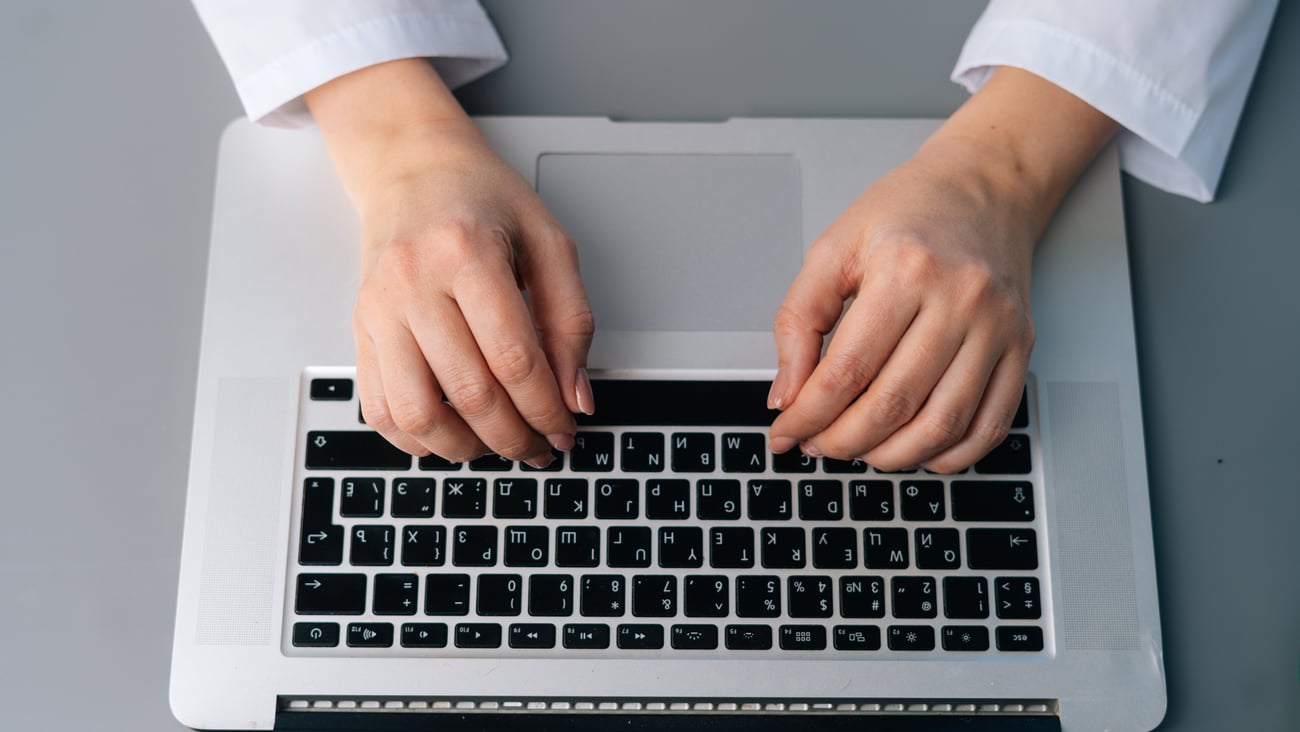 Mains d'une professionnelle de la santé tapant sur un clavier d'ordinateur portable