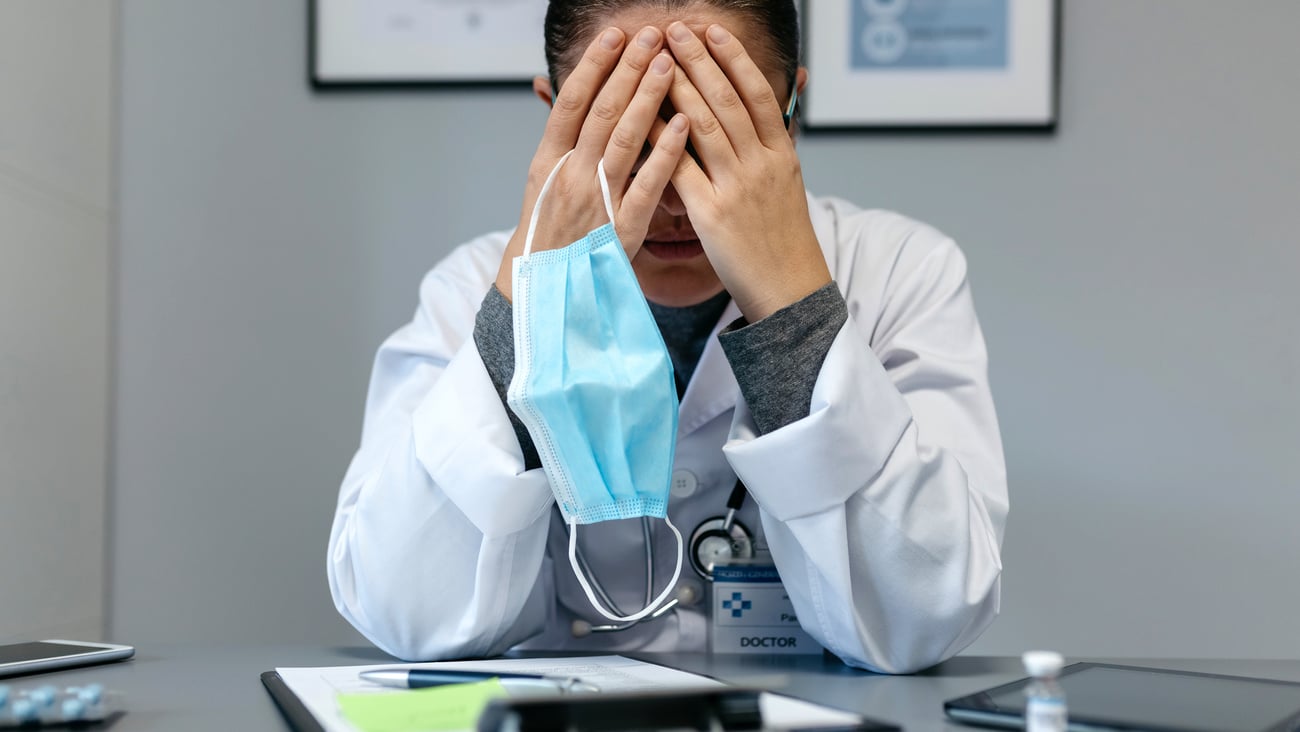 Médecin fatiguée qui se prend la tête à deux mains