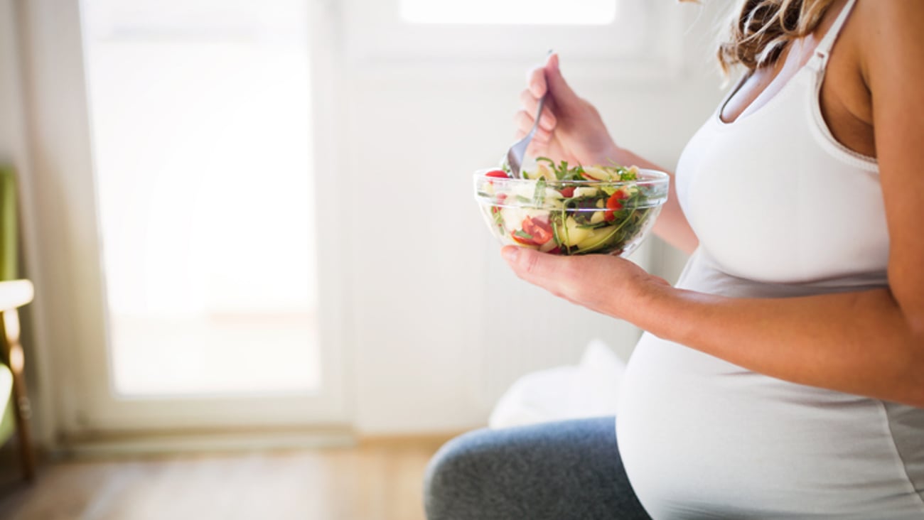 Une femme enceinte mange une salade composée d'aliments santé.