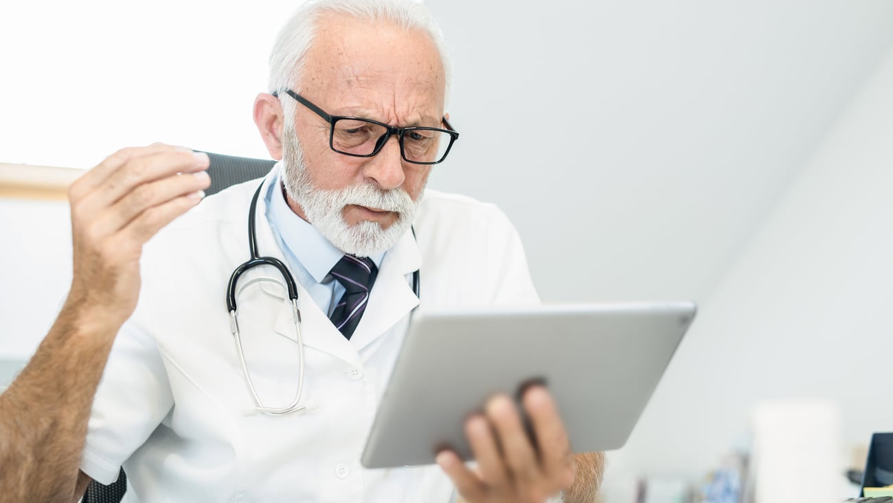 Médecin senior énervé devant sa tablette