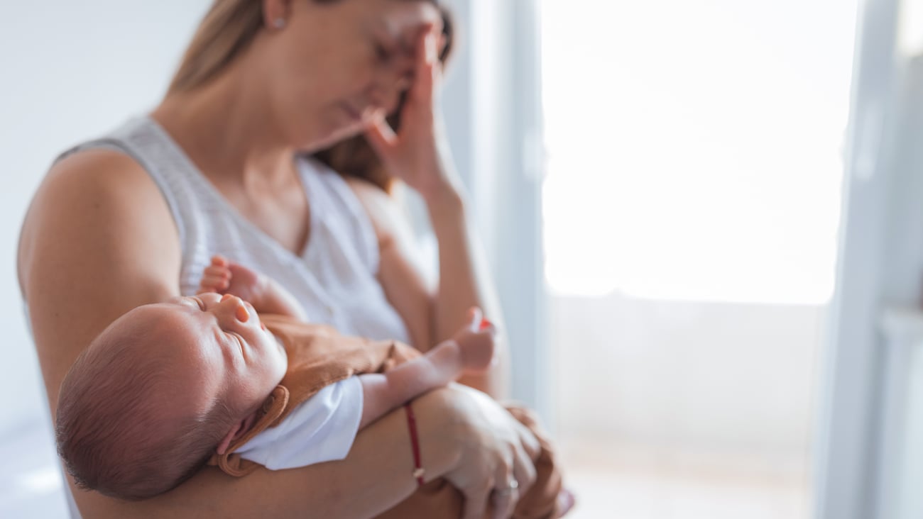 Mère fatiguée avec son bébé au bras.