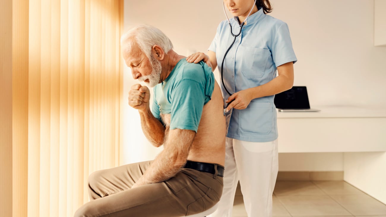 Un homme qui tousse se fait examiner par une médecin.