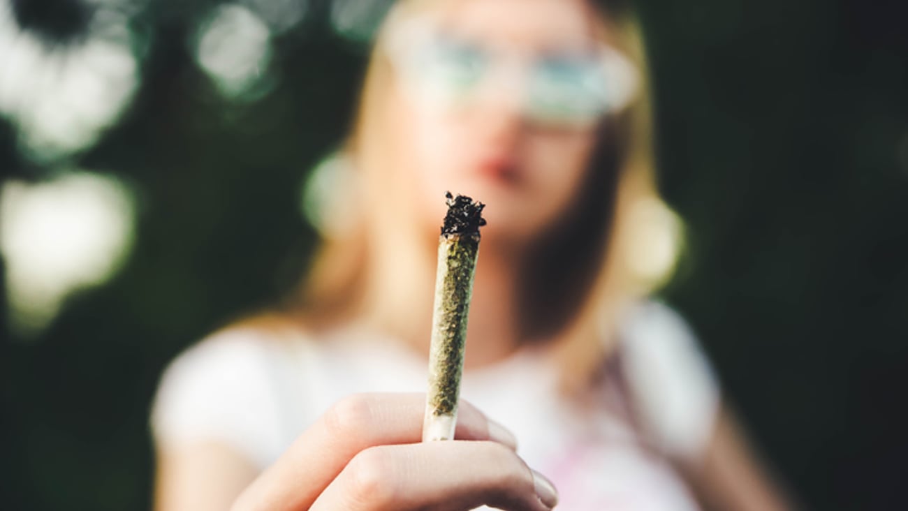 Gros plan sur un joint de cannabis tenu par une femme.