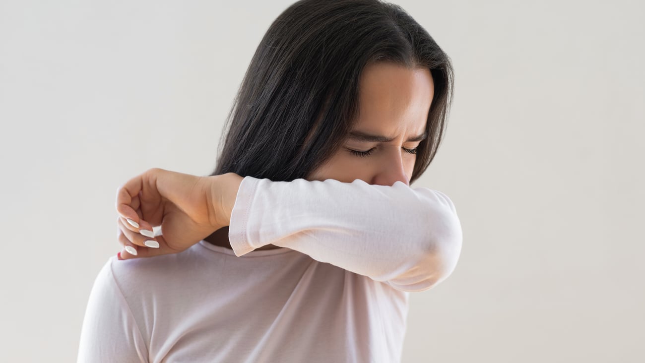 Jeune femme en train de tousser dans son coude