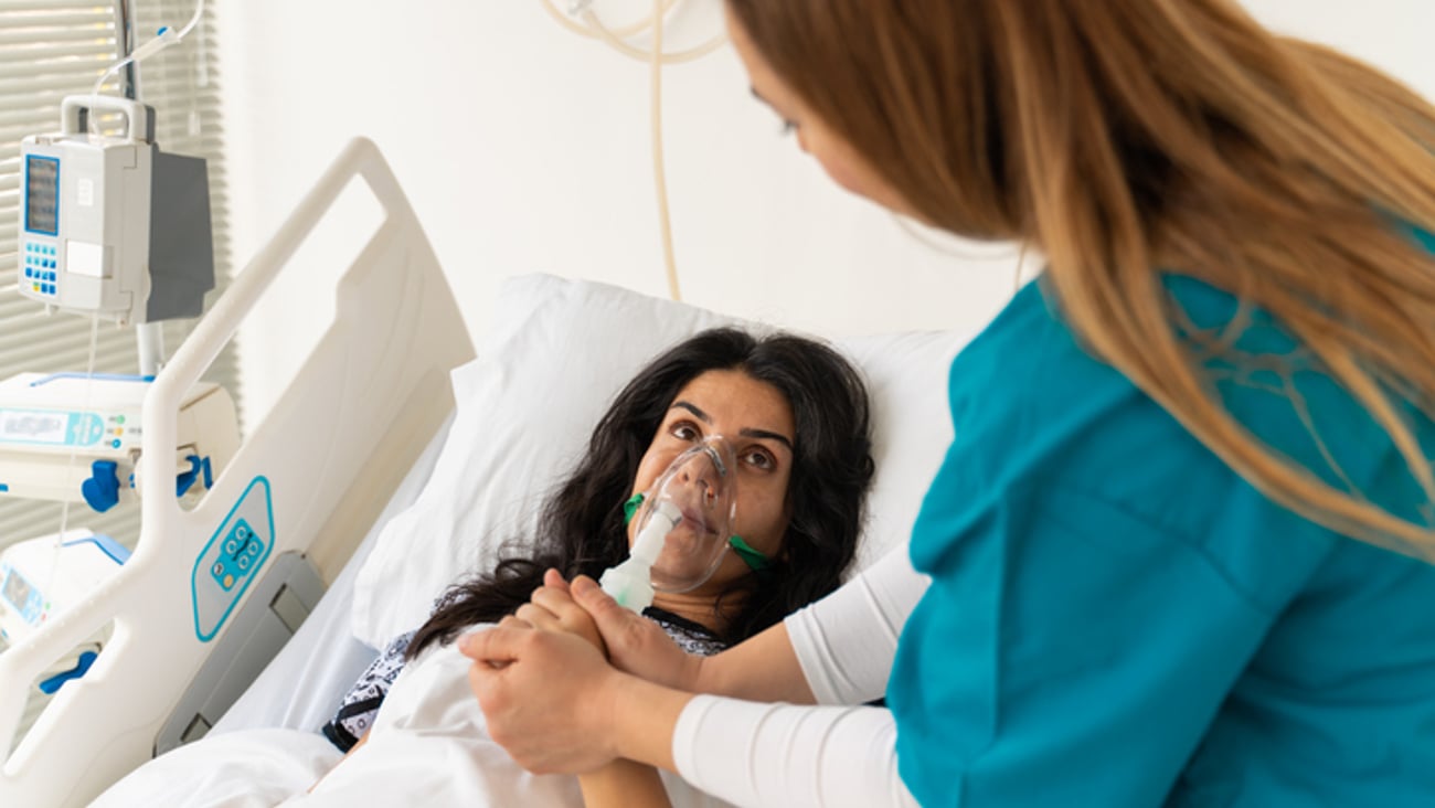 Une patiente en difficulté respiratoire est réconfortée par une infirmière