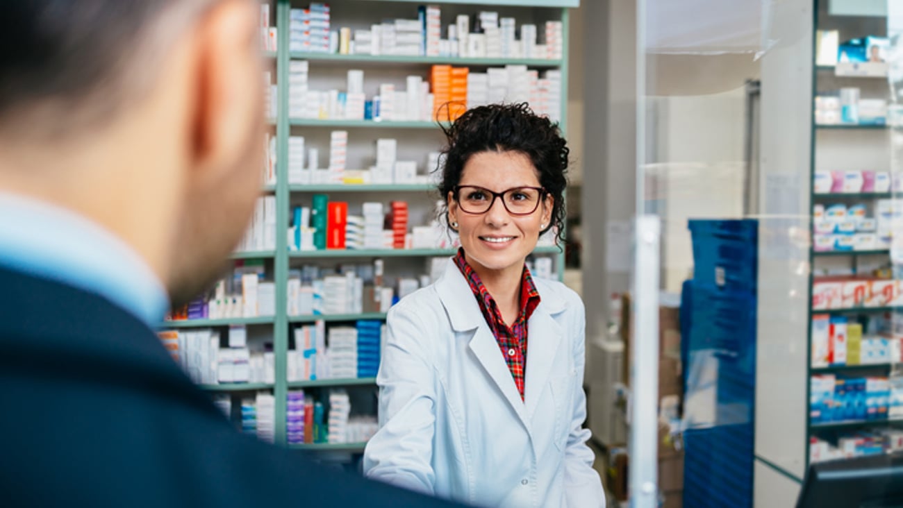 Une pharmacienne sert la main à un client en costume cravate
