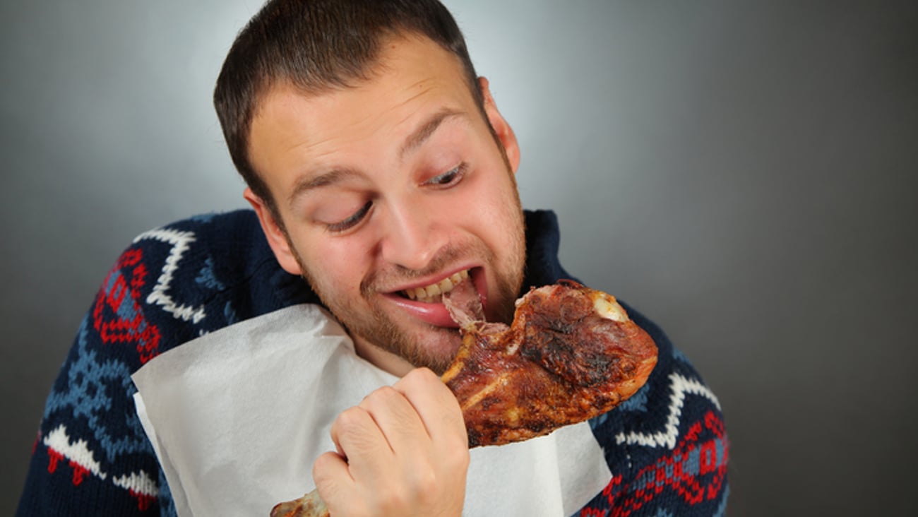 un homme mange une cuisse de poulet