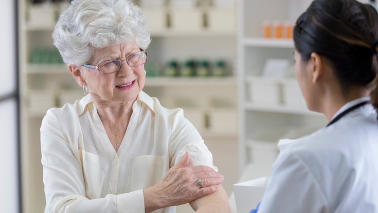 Une personne âgée souffre d'une douleur au bras, à la pharmacie.