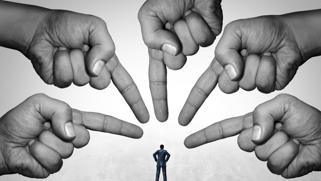 Plusieurs mains pointent une personne en la tenant pour responsable