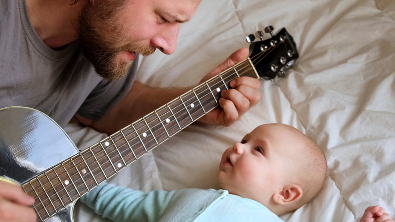 Un père chante des chansons à son bébé, accompagné d'une guitare.