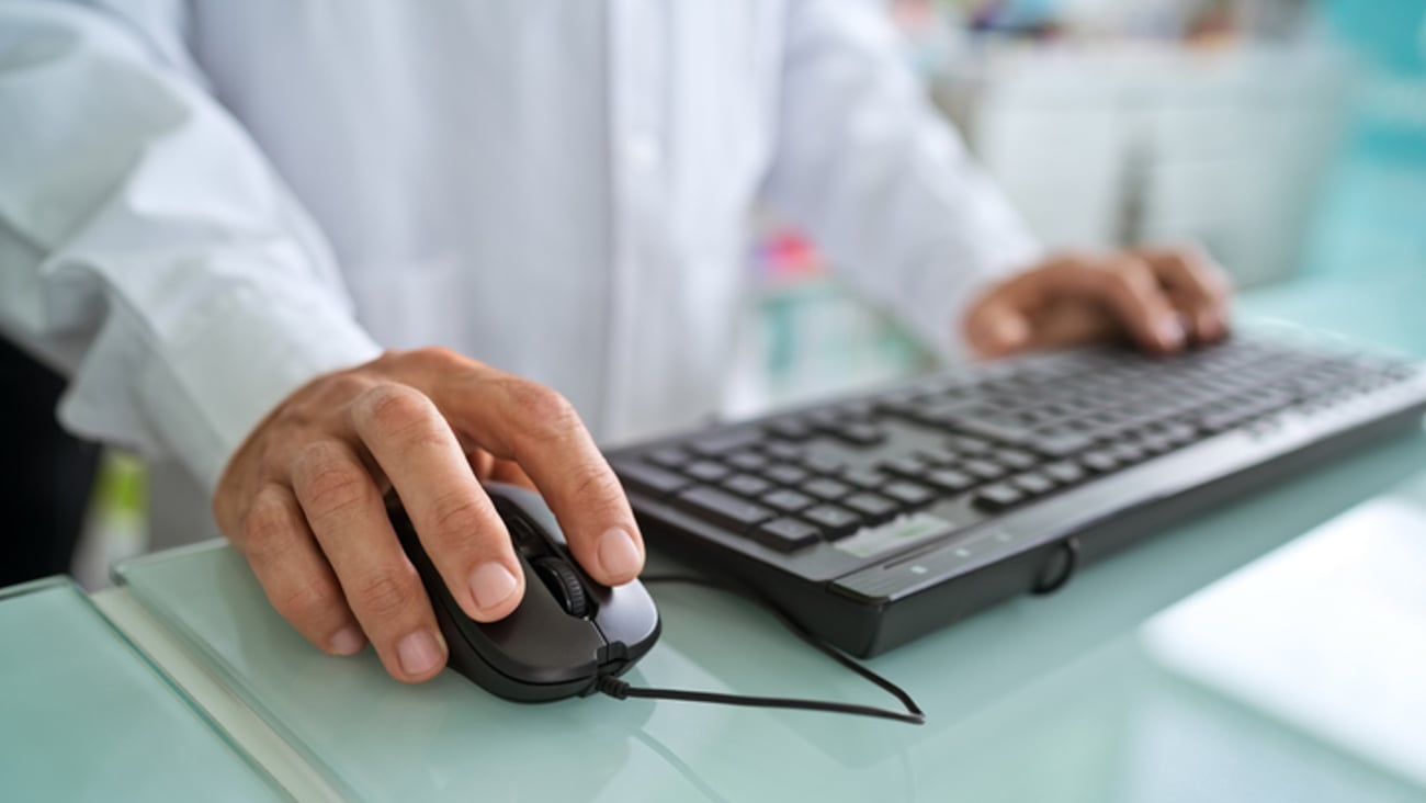 Un pharmacien tape sur un clavier d'ordinateur et utilise une souris