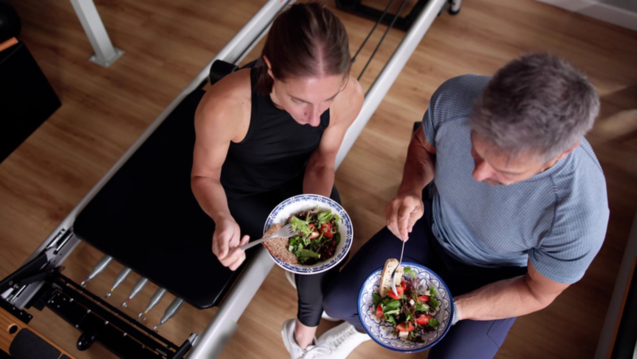 Un couple dans la cinquantaine mange un lunch santé après avoir fait de l'exercice.
