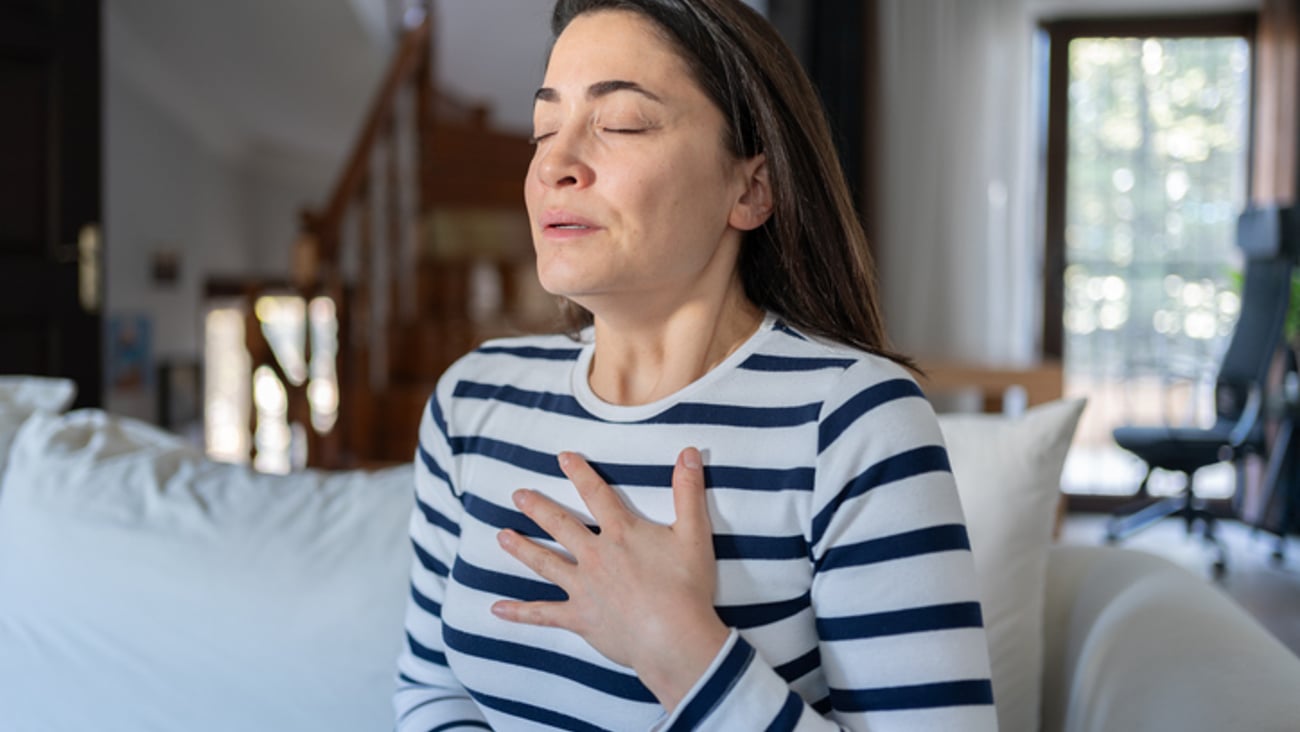 Une femme se tient la poitirine à cause d'une douleur cardiaque