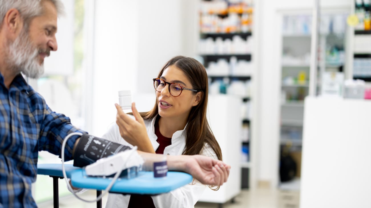 Une technicienne en pharmacie ou pharmacienne prend la tension d'un patient