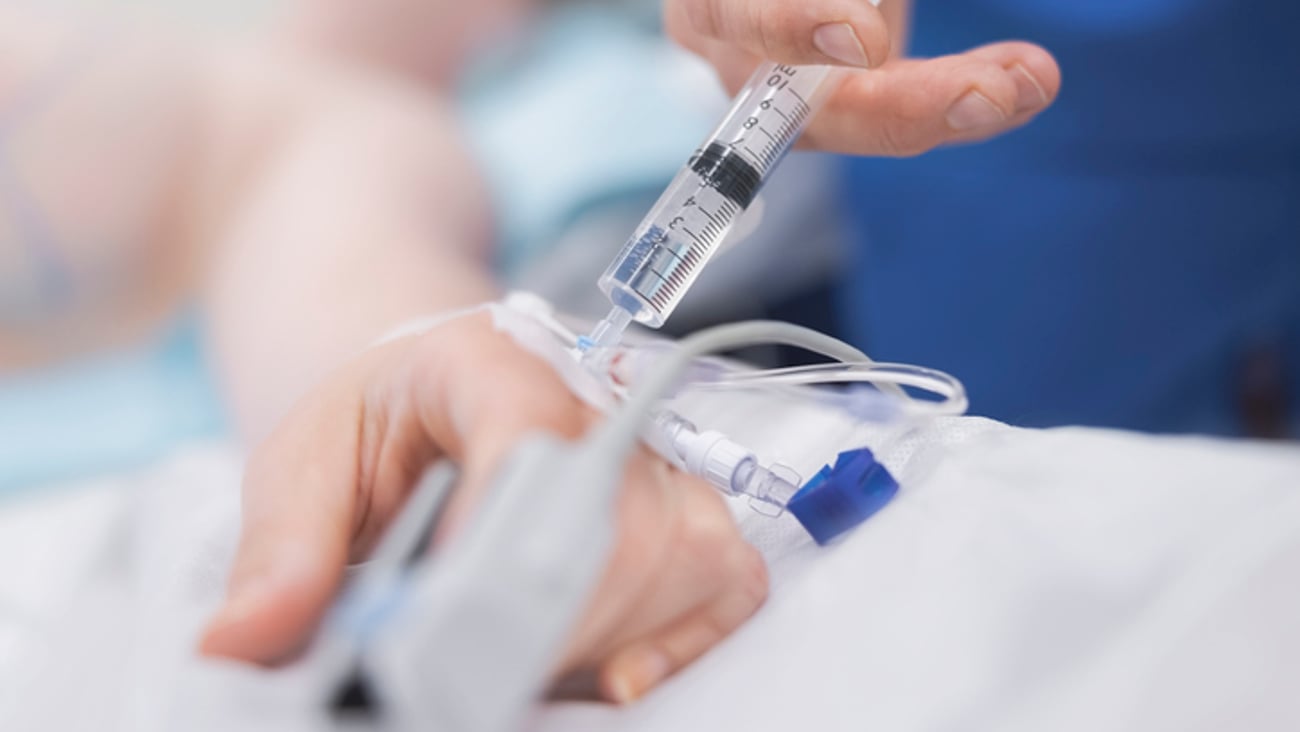 Un soignant anesthésie sa patiente avec une seringue en intraveineuse