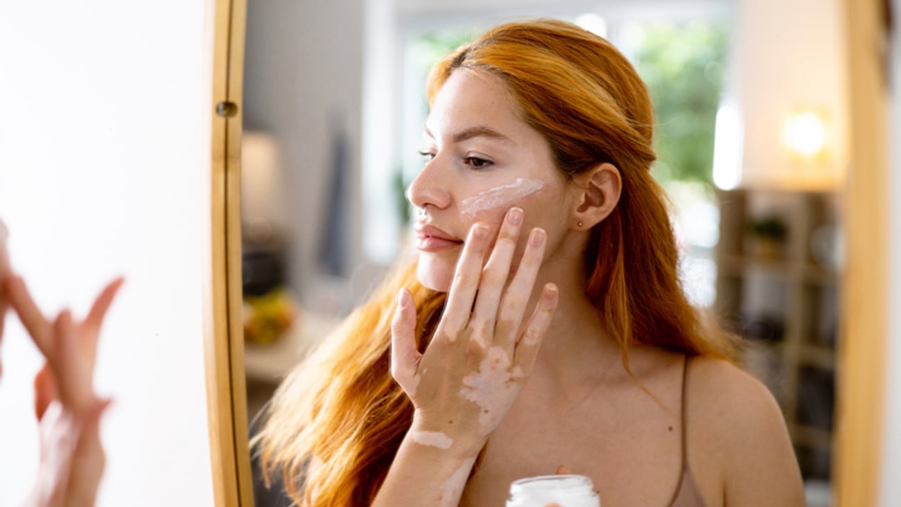 Une femme atteinte de vitiligo applique un traitement topique.