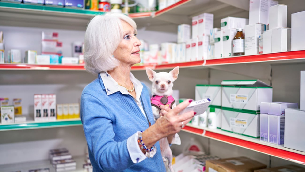 Une cliente et son chien regardent les médicaments dans une pharmacie