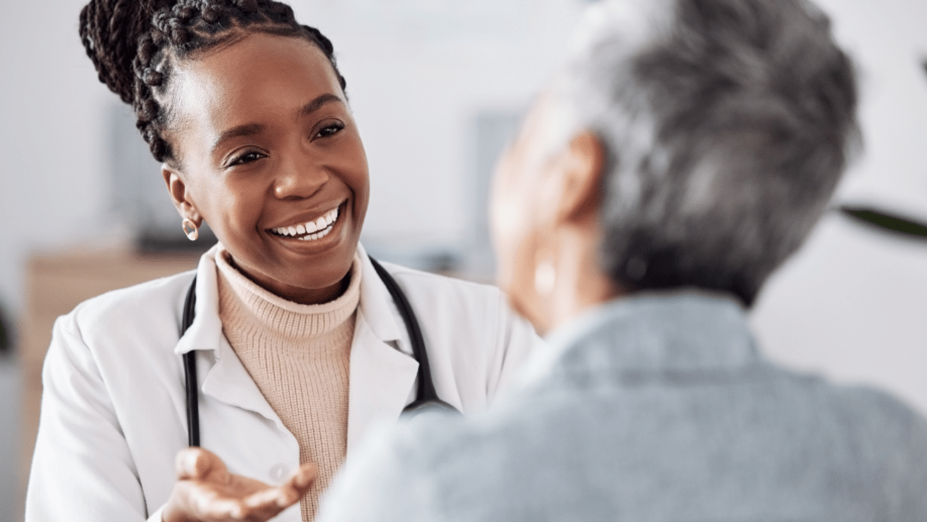 Une femme médecin souriante parle à un patient dans un cabinet médical.