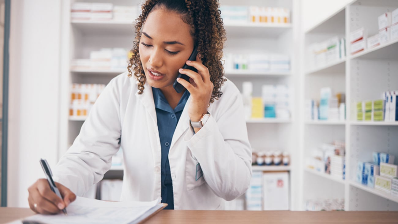 Une pharmacienne parle au téléphone et écrit