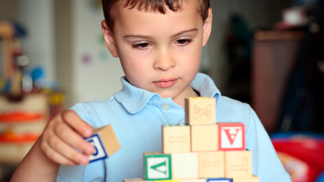 Un enfant autiste joue avec des cubes de bois