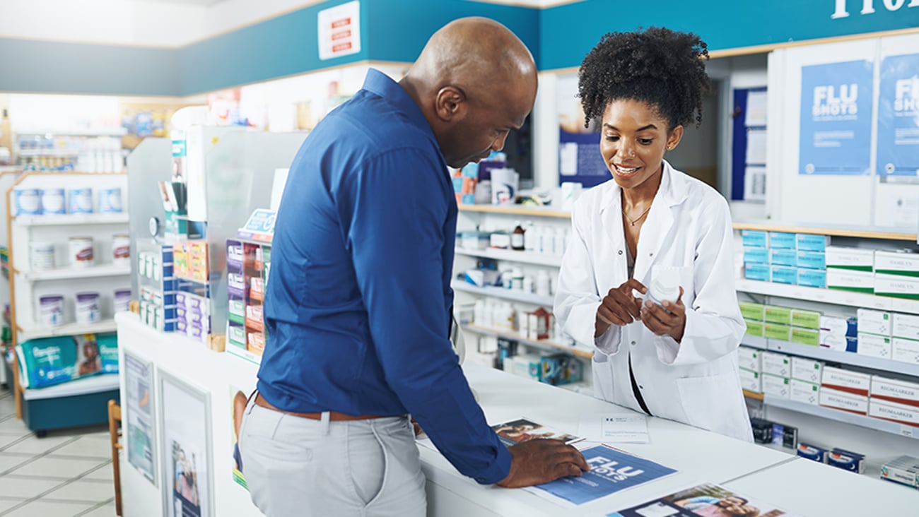 Pharmacien conseillant un client au comptoir de la pharmacie.