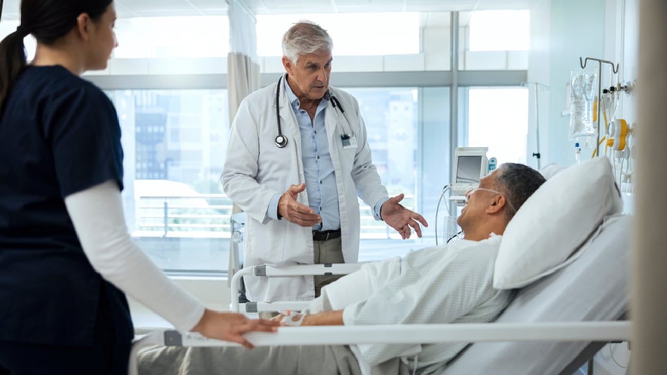 Un médecin discute avec un patient alité à l'hôpital.