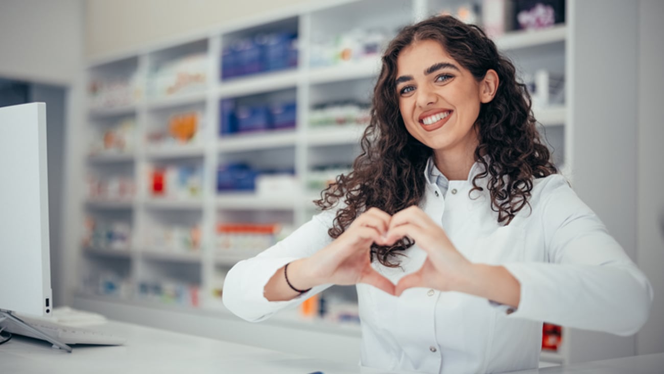 Une pharmacienne souriante fait un coeur avec ses mains