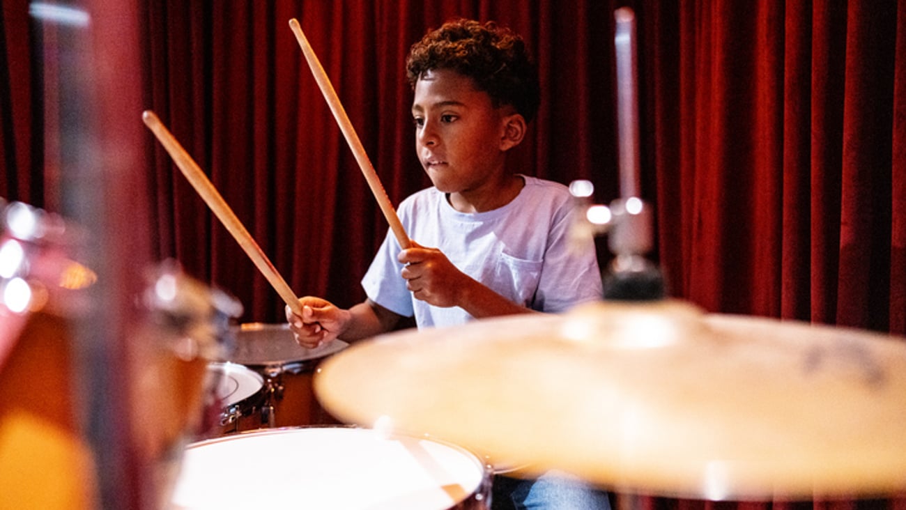 Un enfant joue de la batterie à l'école.