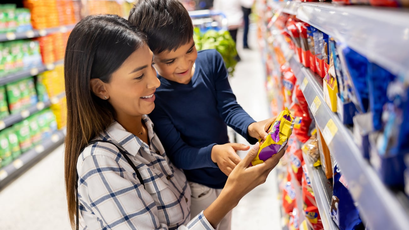 Une femme regarde un emballage d'aliment avec son fils. Crédit photo: andresr/ Getty Images