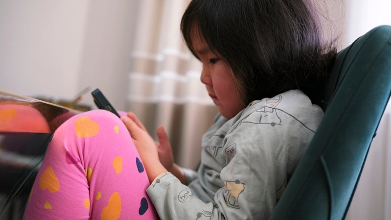 Une fillette en surpoids regarde un cellulaire.