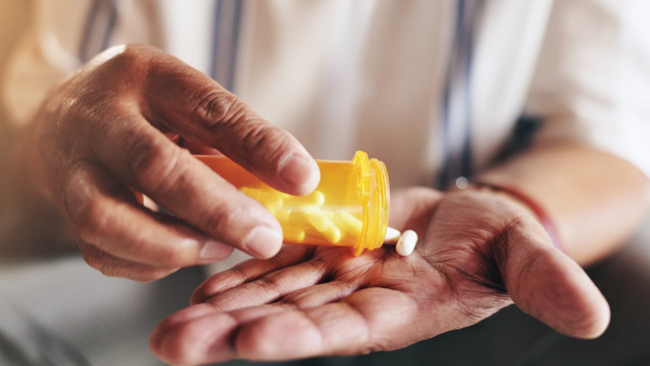 Une personne âgée verse des pilules dans sa main.