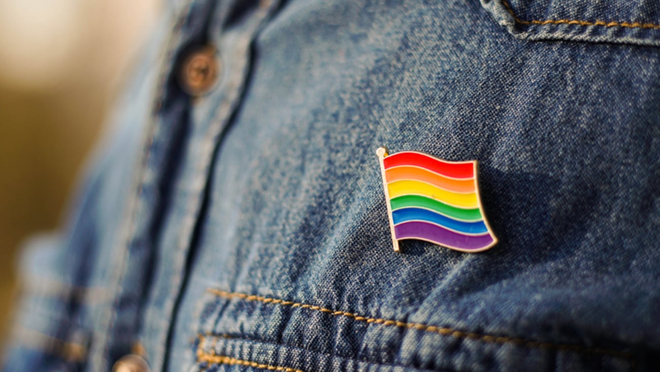Une pin lgbt+ sur une veste en jeans.