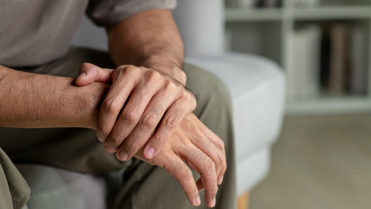 Un homme a les bras croisés, sur un divan.