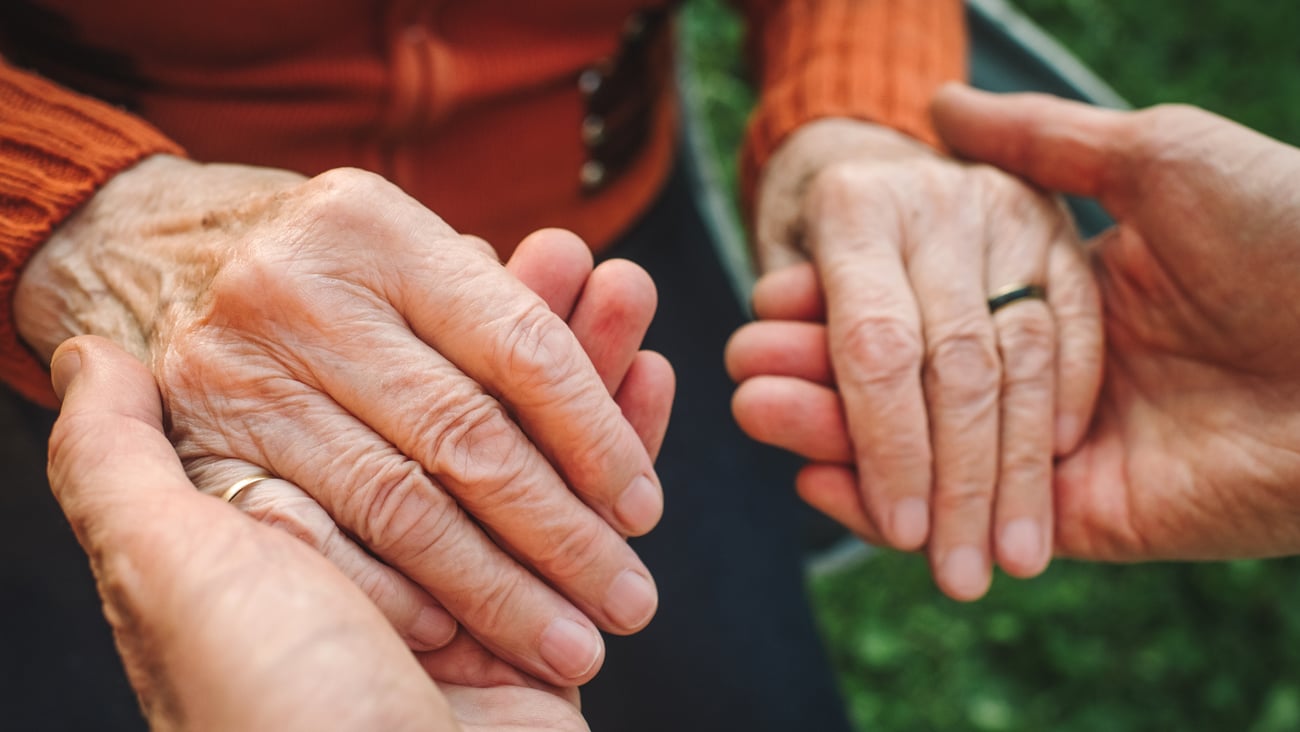 Une personne tient les mains d'une aînée. Crédit photo: ArtMarie/ Getty Images