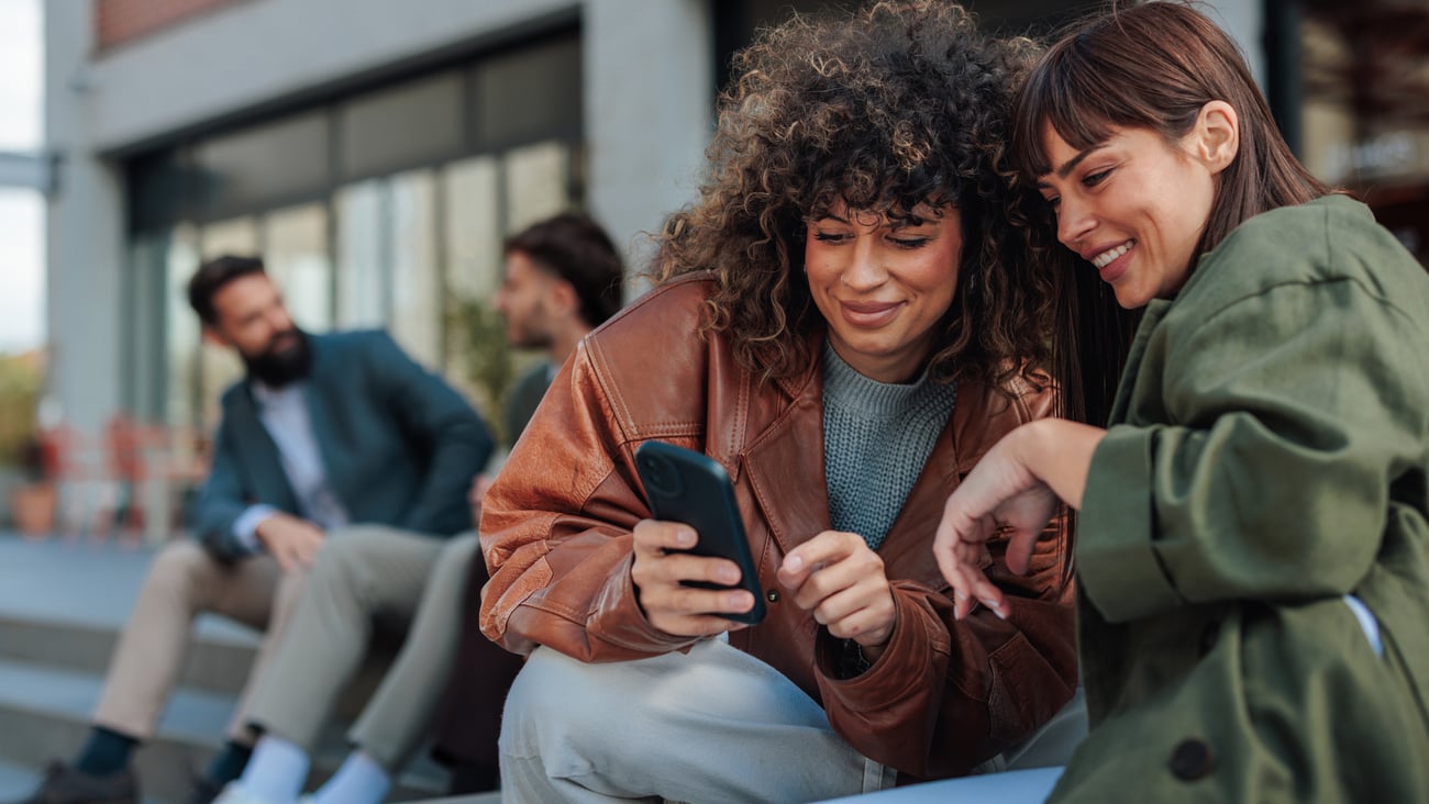 Deux femmes discutent en regardant un téléphone intelligent. Crédit photo: Dimensions/Getty Images