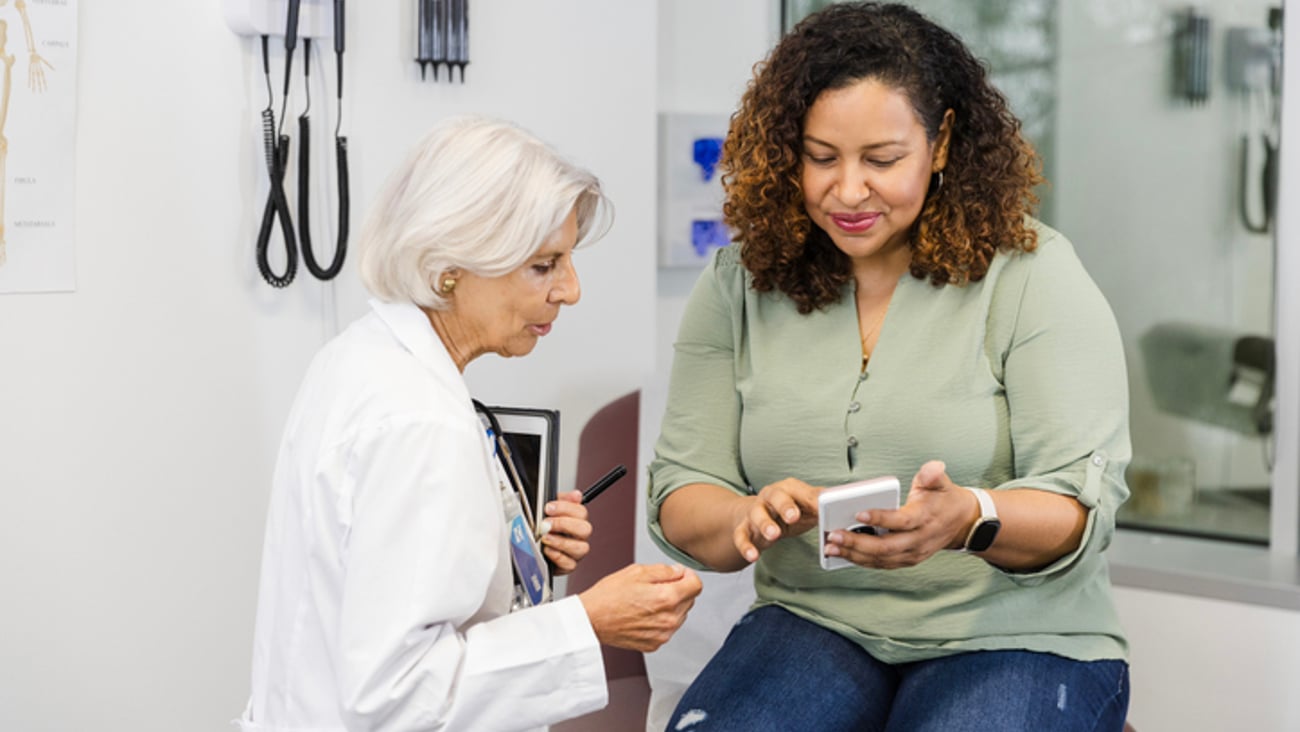 Une patiente montre un contenu à sa médecin sur son téléphone, lors d'une consultation médicale.