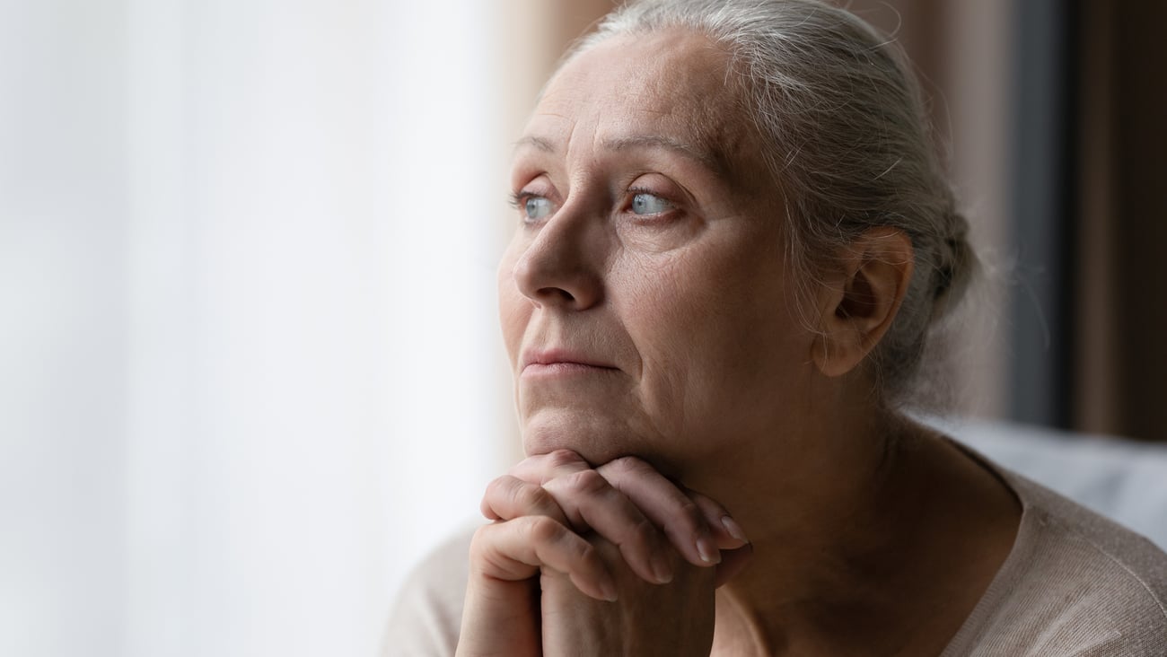 Une femme âgée regarde par la fenêtre. Crédit photo: fizkes/ Getty Images 