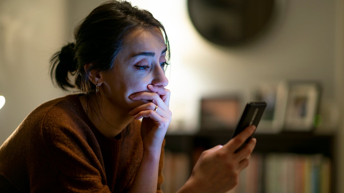 Une femme triste regarde son téléphone. Crédit photo: ilkermetinkursova/Getty Images