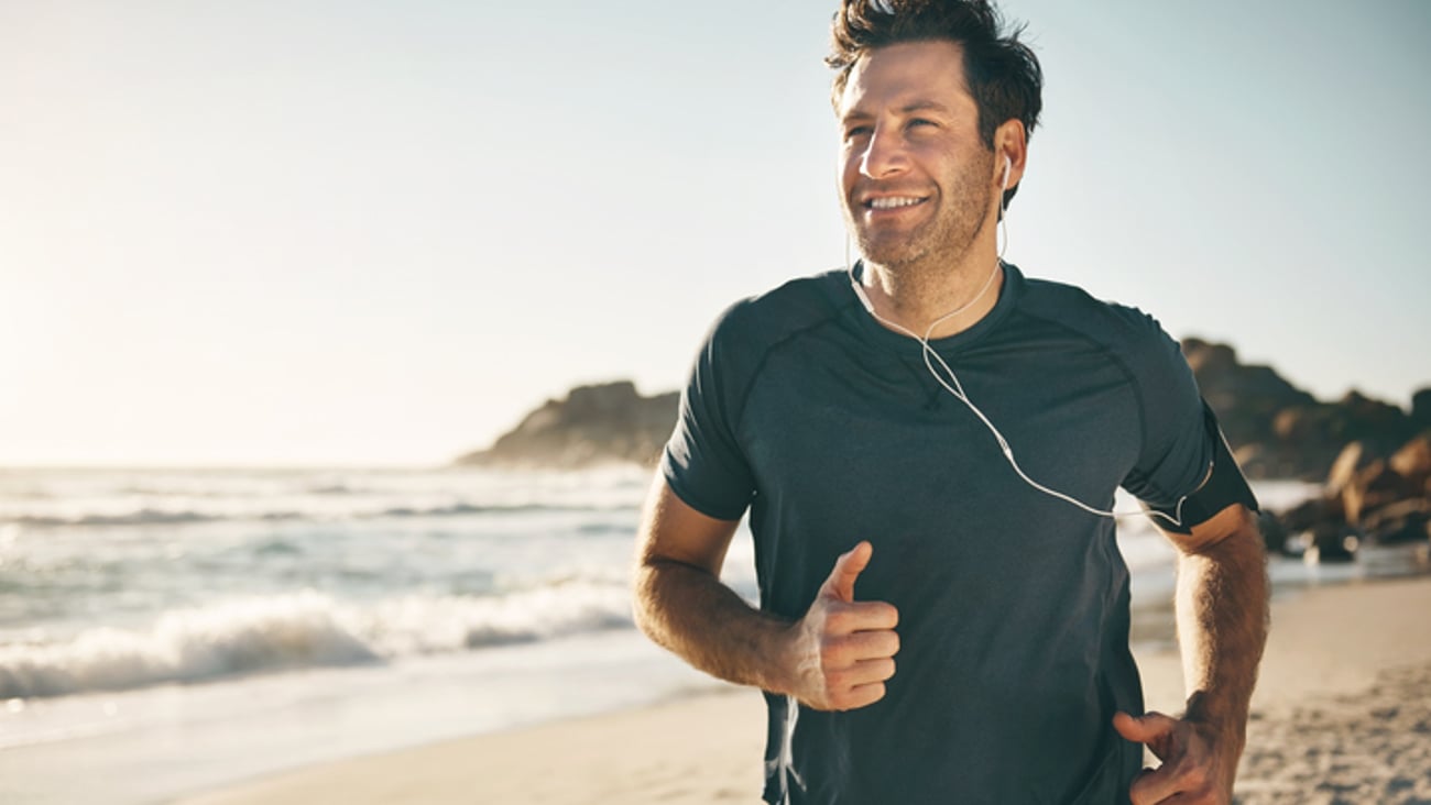 Un homme fait son jogging sur une plage.