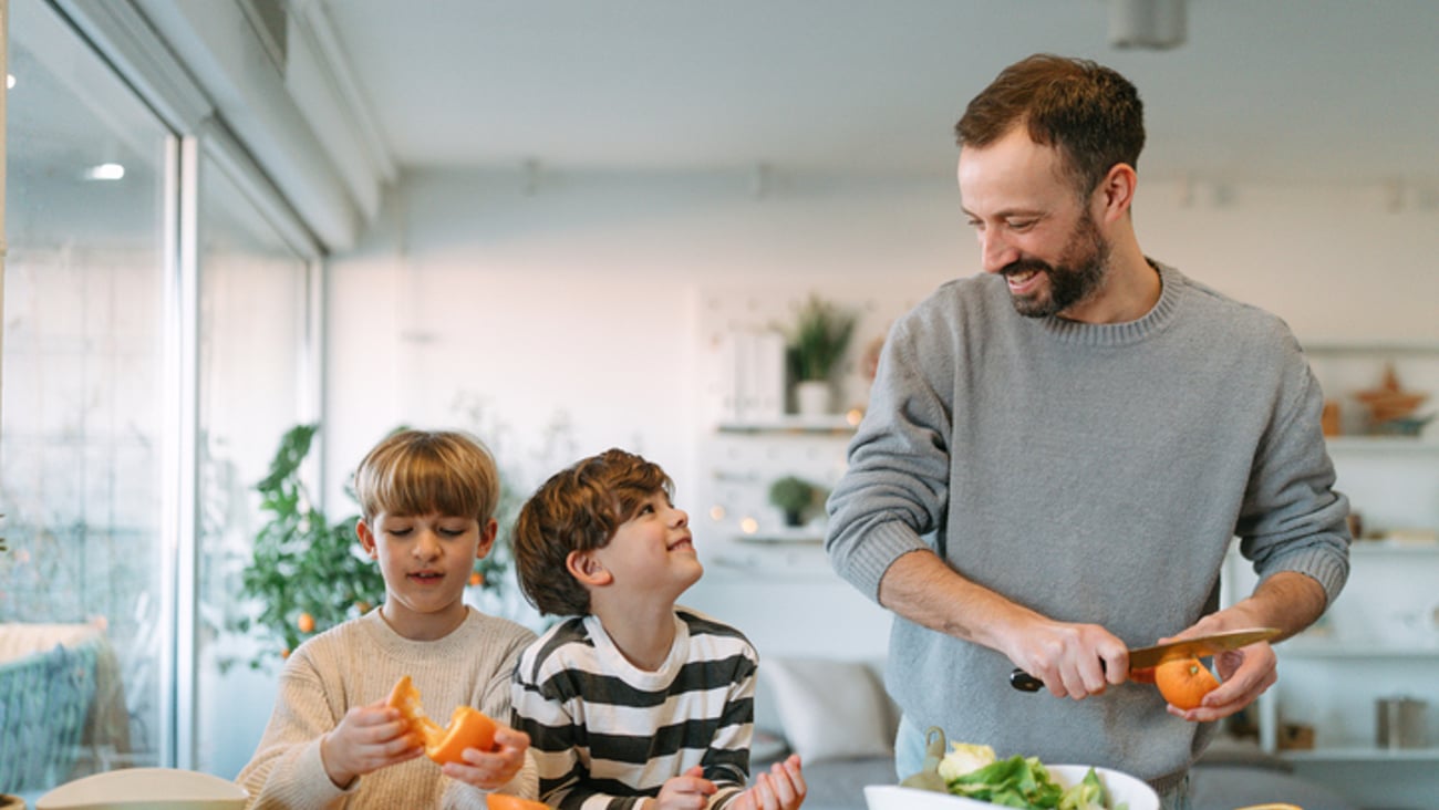 Un père prépare un repas santé avec ses enfants, à la maison.