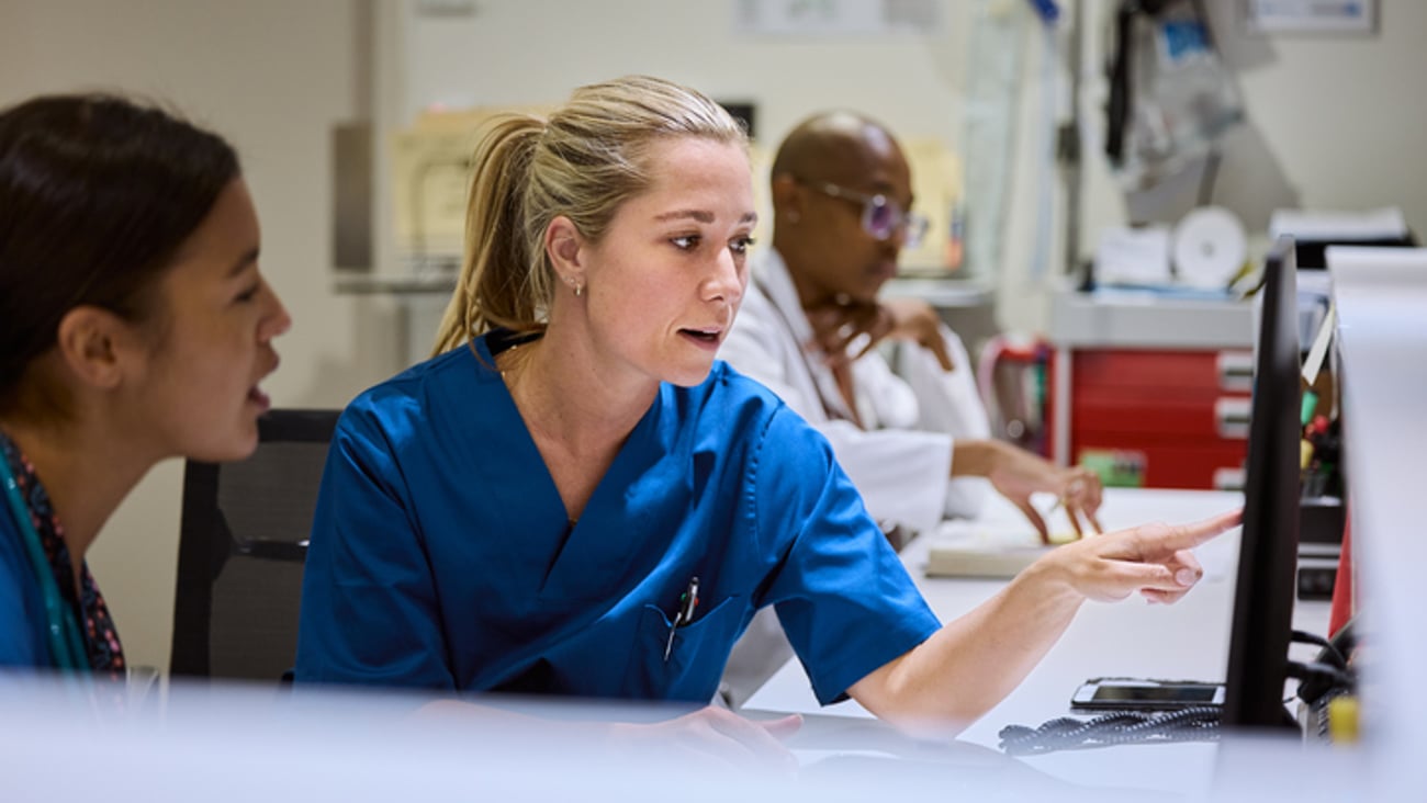 Des infirmières ou des médecins discutent devant un ordinateur dans un hôpital.