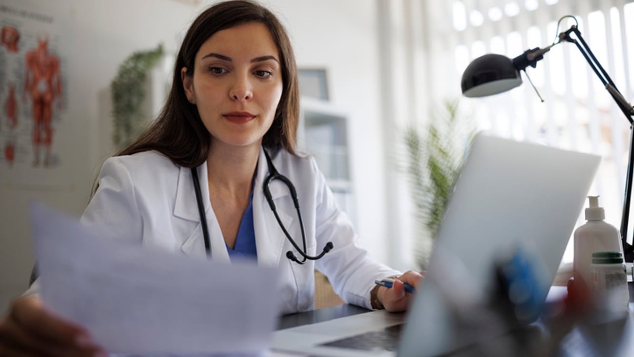 Une médecin, entre sa paperasse et son ordinateur.