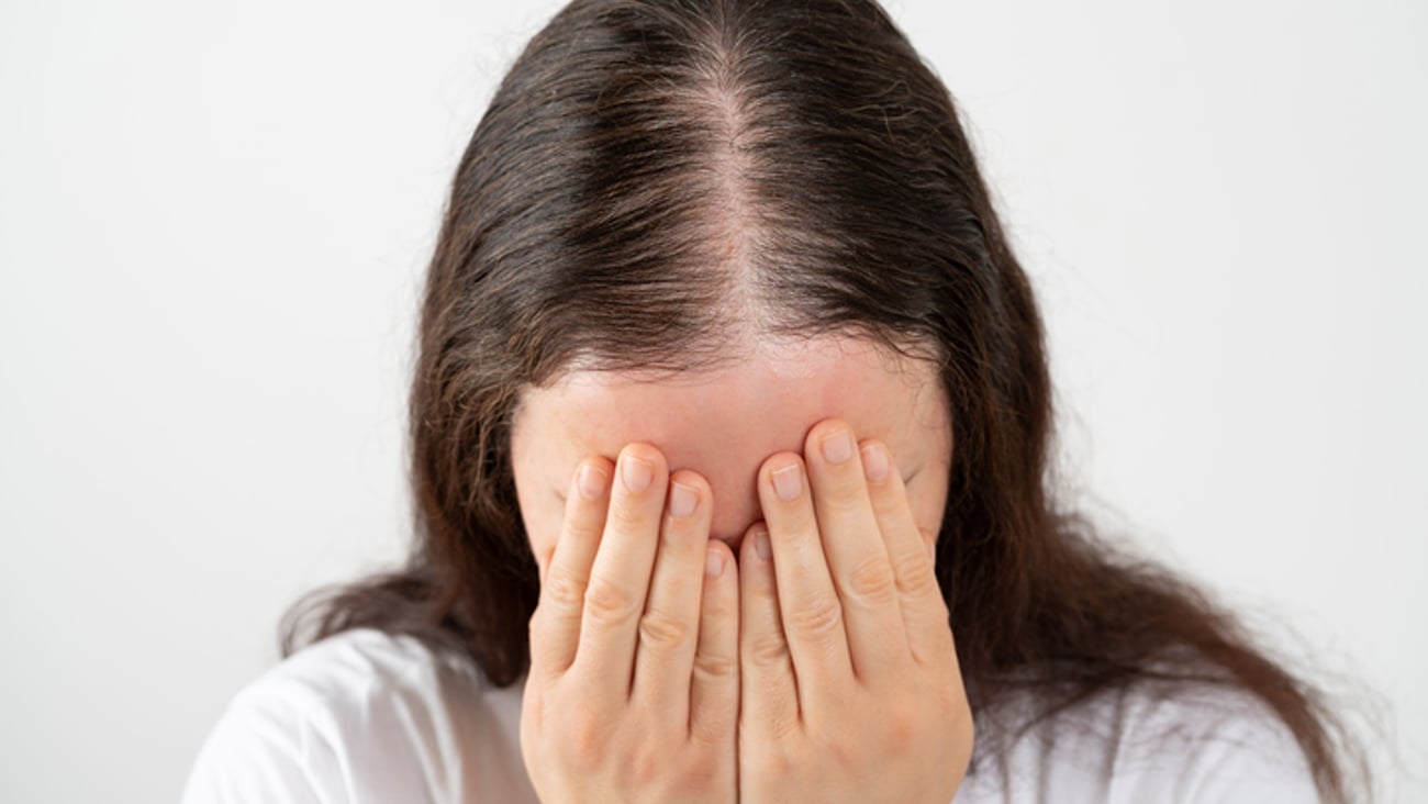 Une femme pleure à cause de sa perte de cheveux