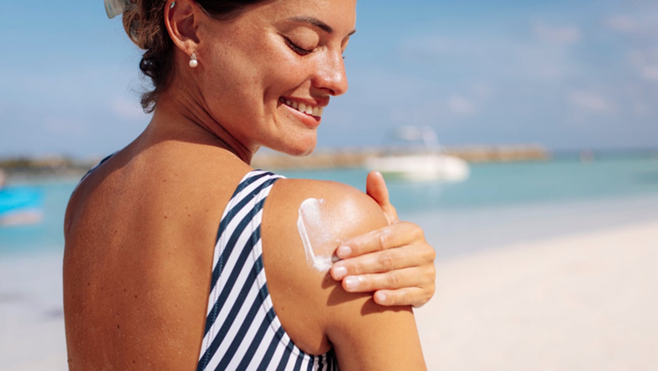 Une femme s'applique de la crème solaire à la plage