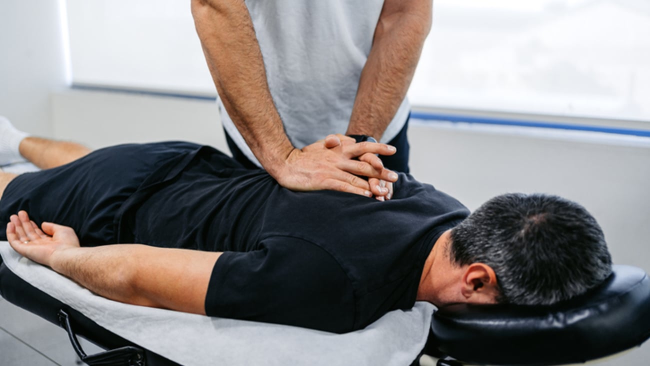Un ostéopathe manipule le dos de son patient allongé