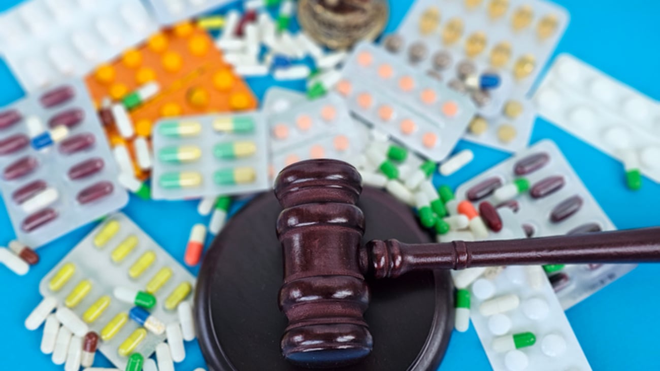 Représentation de la sanction d'un pharmacien, avec un marteau de justice entouré de médicaments.