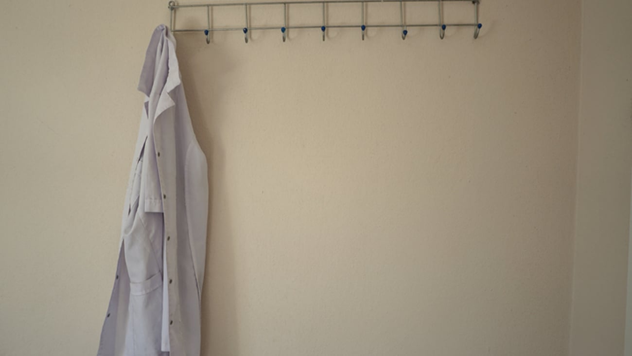 Une blouse blanche / un sarrau accroché à un porte-manteau